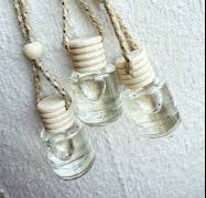 Three small Car diffuser bottles with  stoppers hanging on a textured surface